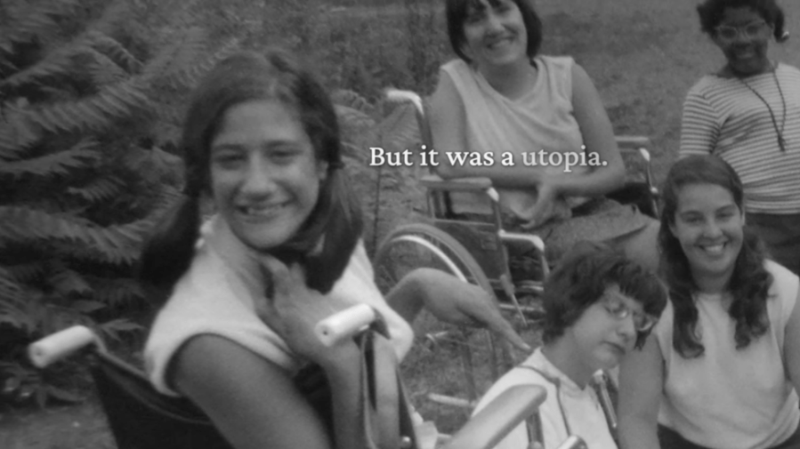 Denise Sherer Jacobson (left), a dark-haired young woman in a wheelchair, seen in archival footage with open captions of her contemporary spoken narration appearing on the right of the screen.