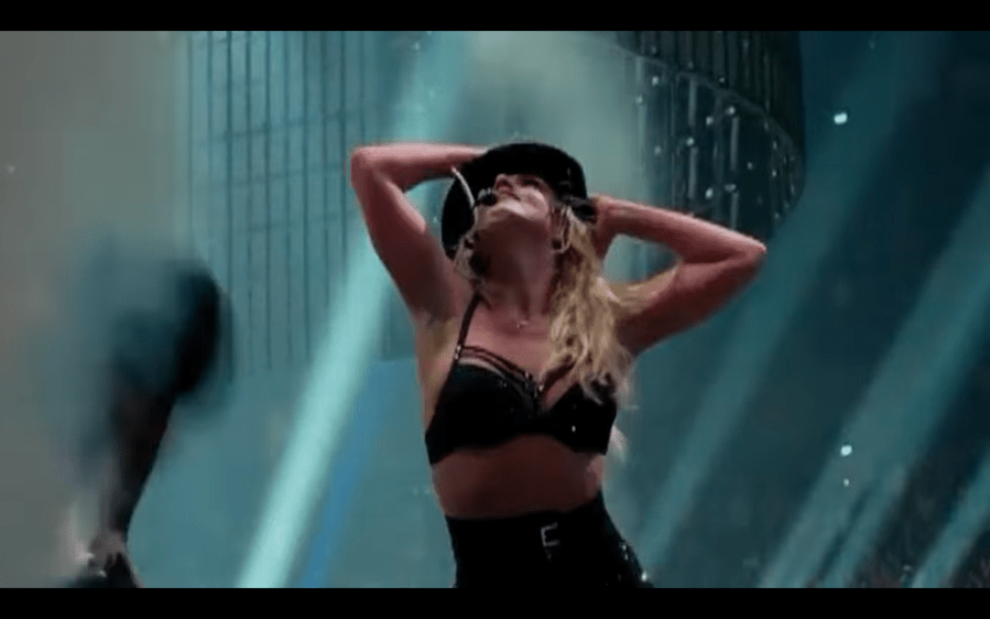 A blonde woman singing and dancing on stage