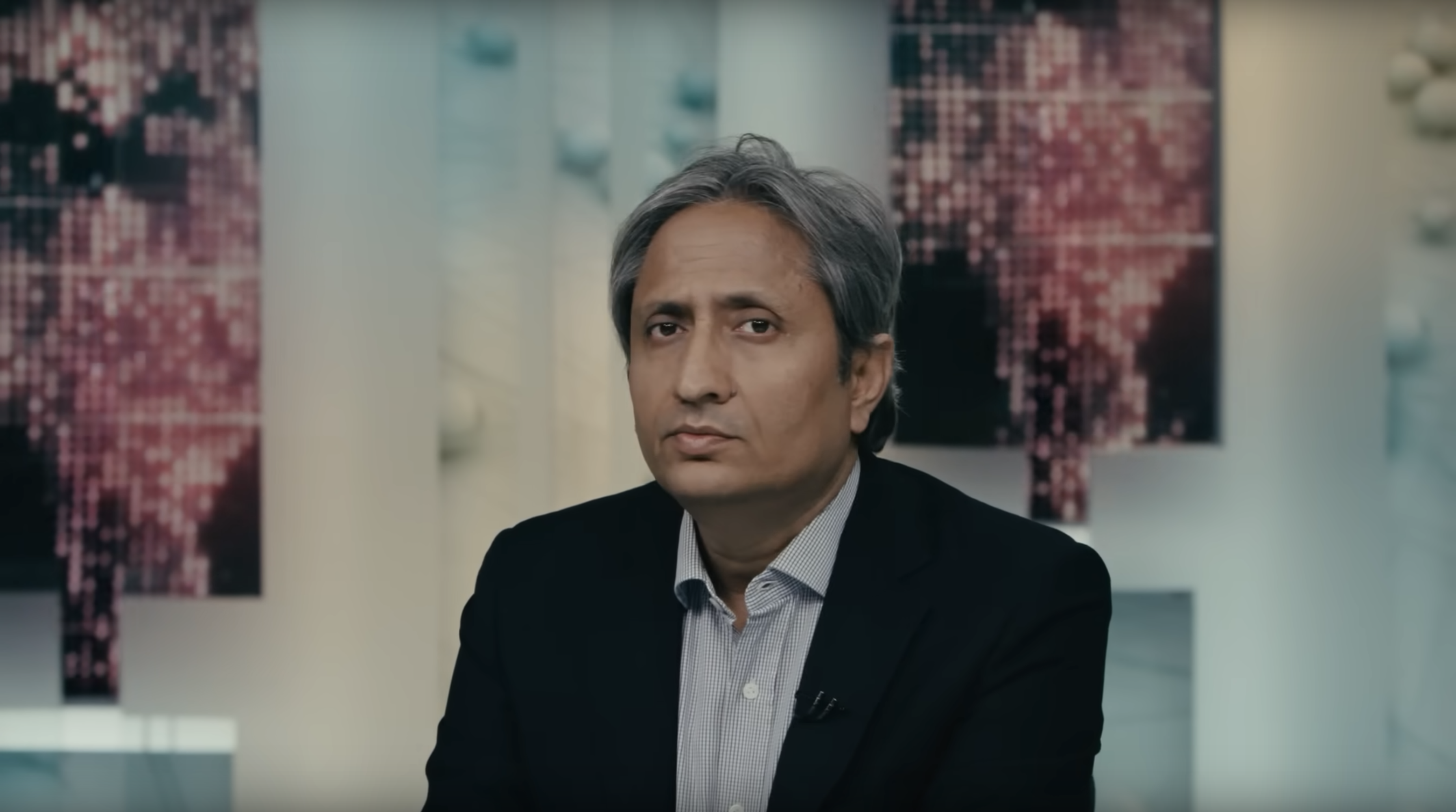 A male Indian journalist staring pensively at the camera