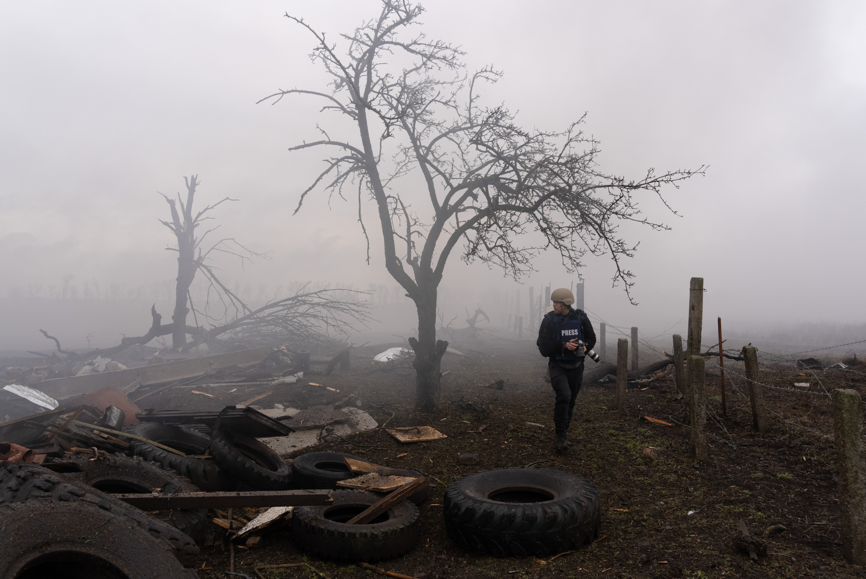 a press photographer walks through a landscape devastated by a bomb attack