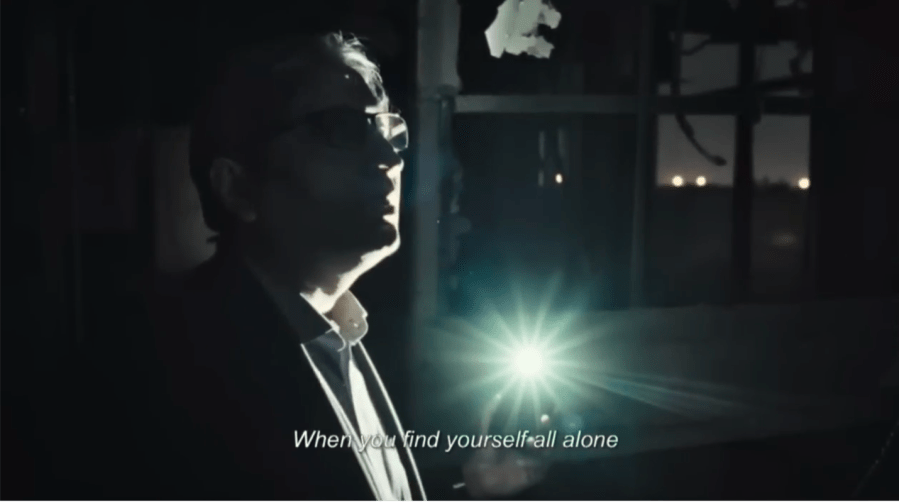 a man walking in the dark using his phone's flashlight for illumination