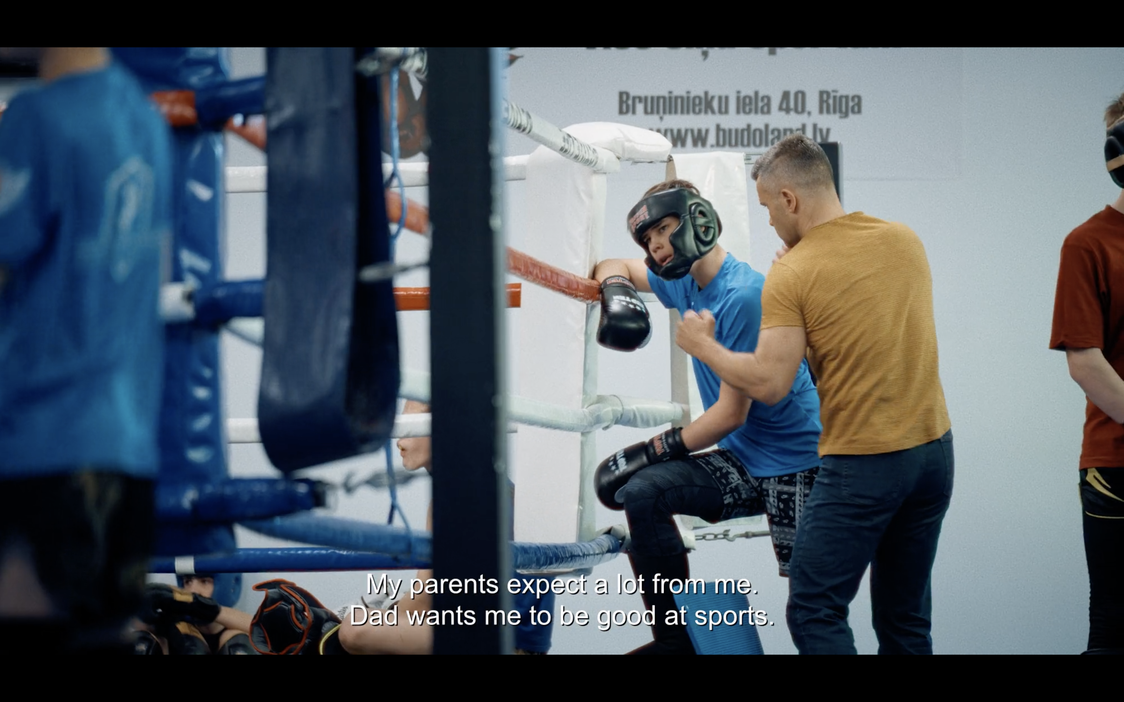 a teenage boy and his father stand outside of a boxing ring