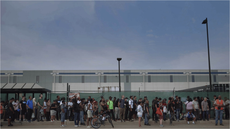 Amazon warehouse workers line up on the sidewalk