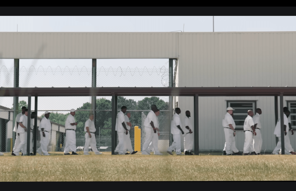 A group of men, dressed in white, walking in the yard of an Alabama prison